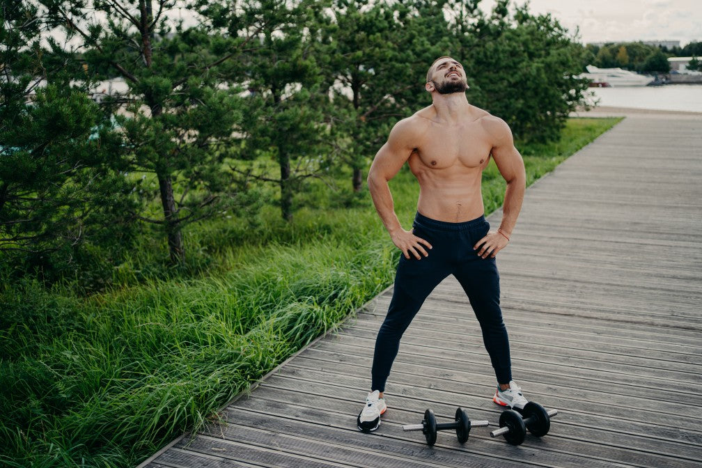 bearded-muscular-man-keeps-hands-on-waist-raises-head-and-breathes-fresh-air-takes-break-after-doing_t20_jLbkLk