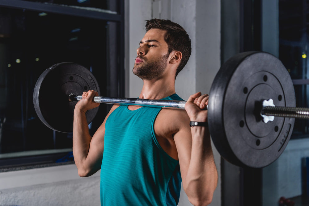 sportsman lifting barbell in sports hall